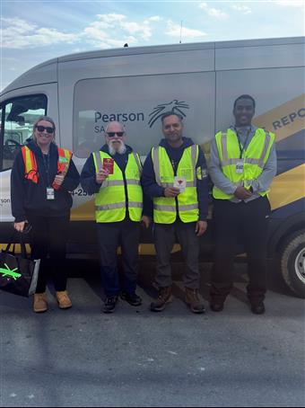 a group of men in safety vests standing in front of a truck
