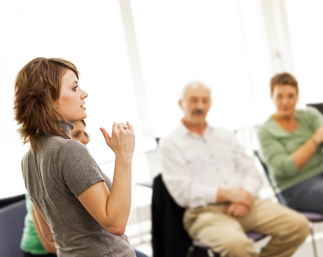 A woman standing in front of her peers during a discussion