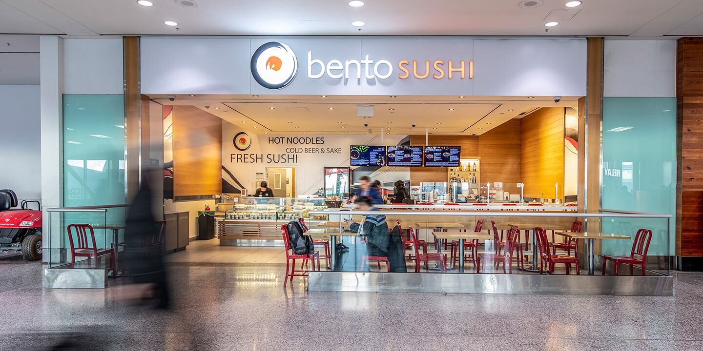 Enseigne de Bento Sushi au-dessus de l’entrée, avec des tables juste à l’extérieur