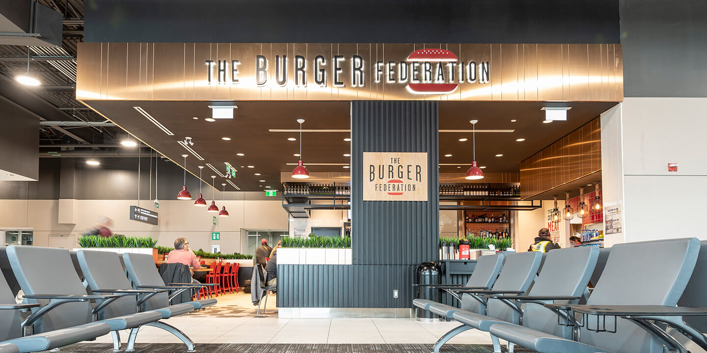 View of Burger Federation open-concept restaurant with brass sign and table seating