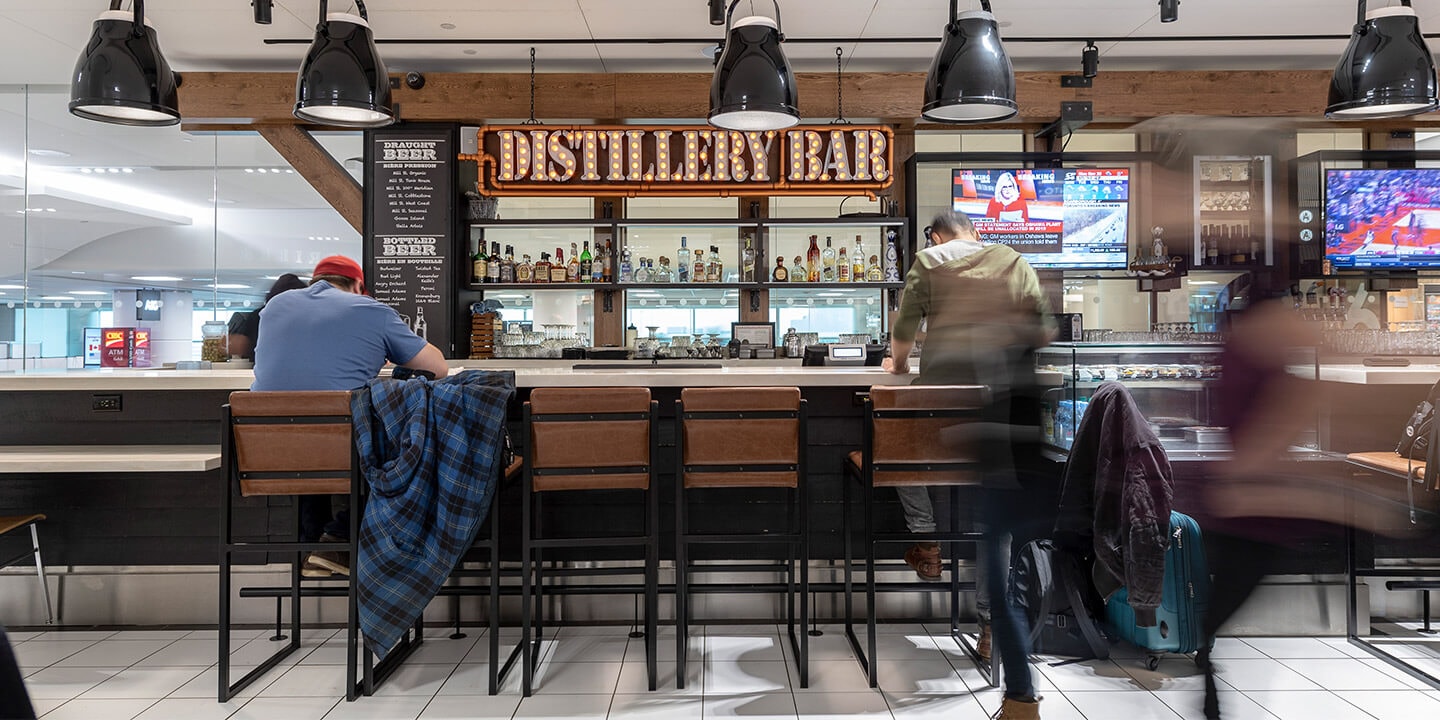 View of bar with Distillery Bar sign, televisions and bar stools