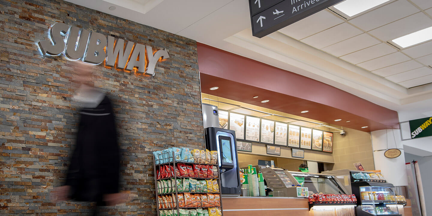 Subway sign on stone wall next to ordering counter, fully open to terminal area